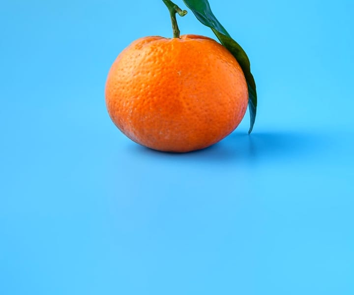 Orange with leaves on blue background